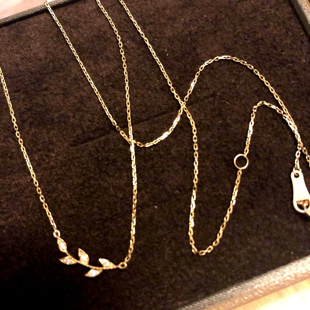 Close-up of agate Laurel Leaf K10 necklace featuring small diamonds on a shiny gold chain