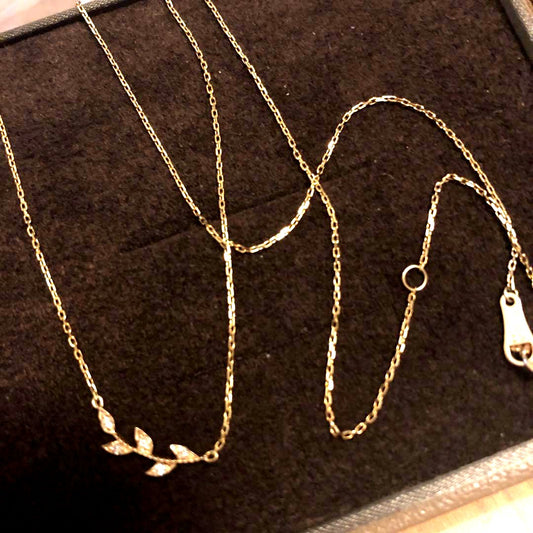 Close-up of agate Laurel Leaf K10 necklace featuring small diamonds on a shiny gold chain