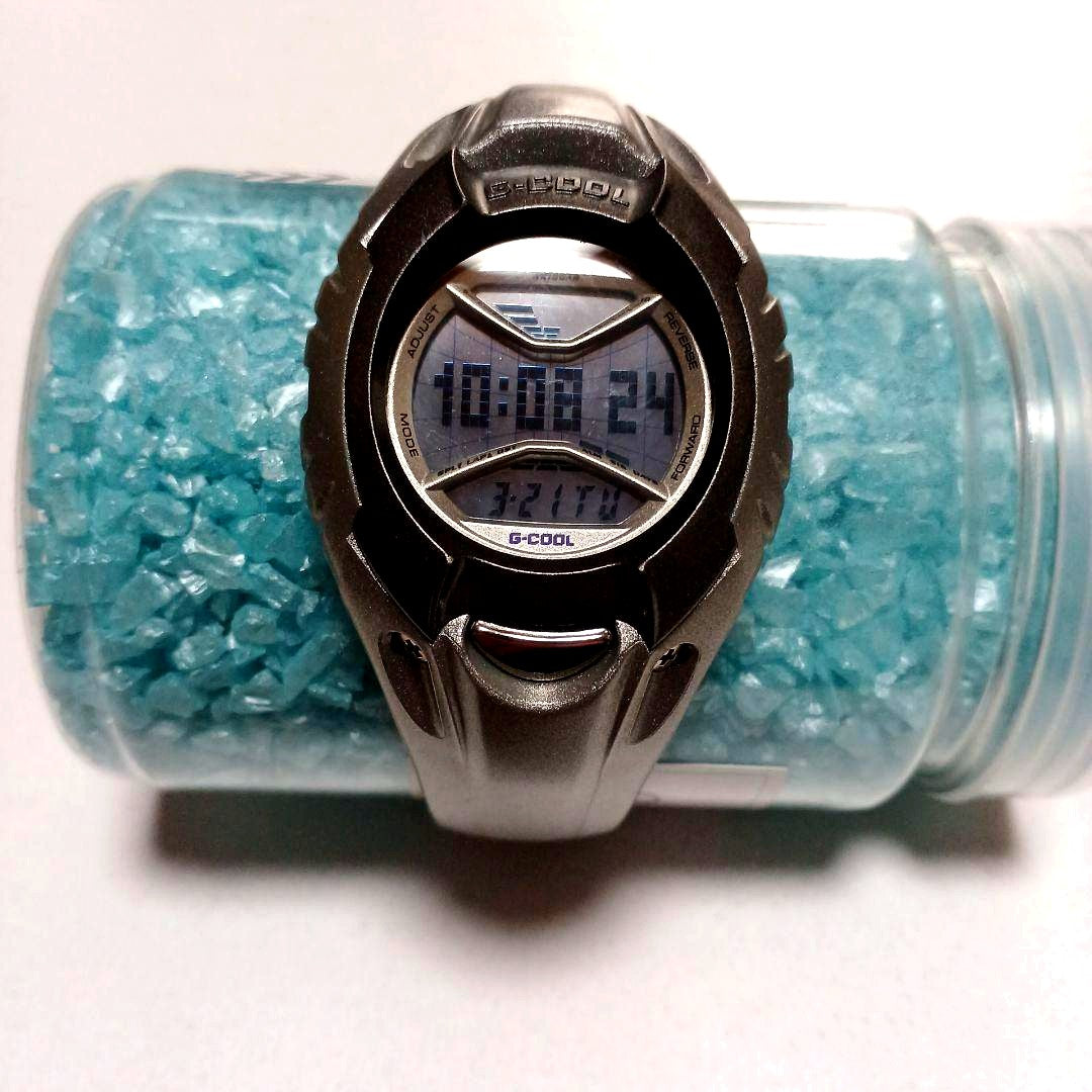 Casio G-Cool wristwatch with clear glass, metal band, and user manual included