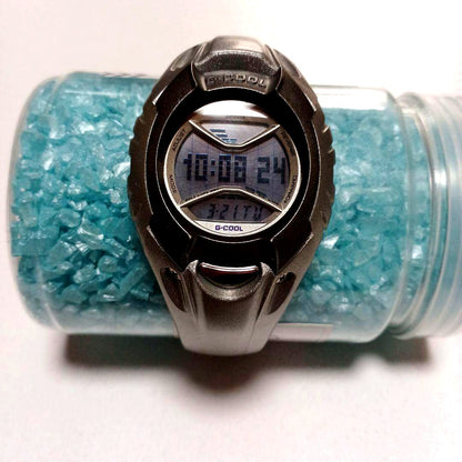 Casio G-Cool wristwatch with clear glass, metal band, and user manual included