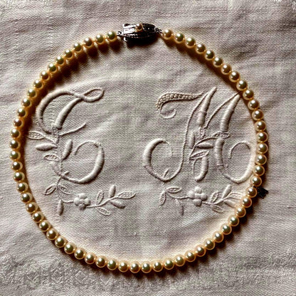 MIKIMOTO pearl choker necklace with 63 round pearls and silver M engraved clasp displayed with original box