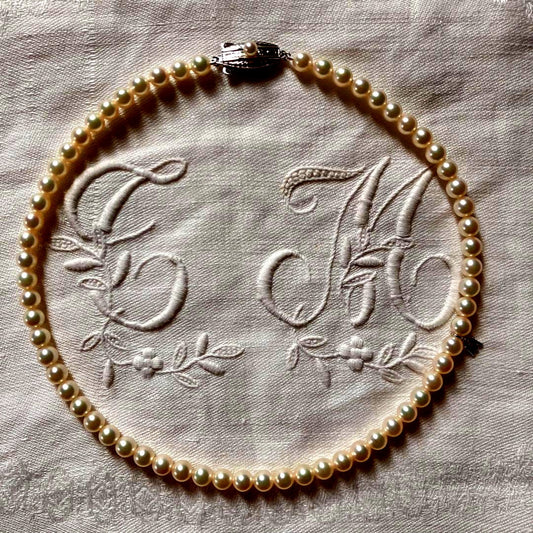 MIKIMOTO pearl choker necklace with 63 round pearls and silver M engraved clasp displayed with original box