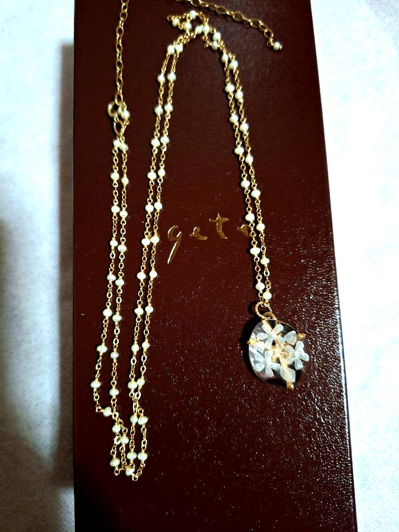 agete flower motif necklace with gold flower pendant and metal chain displayed with dedicated box