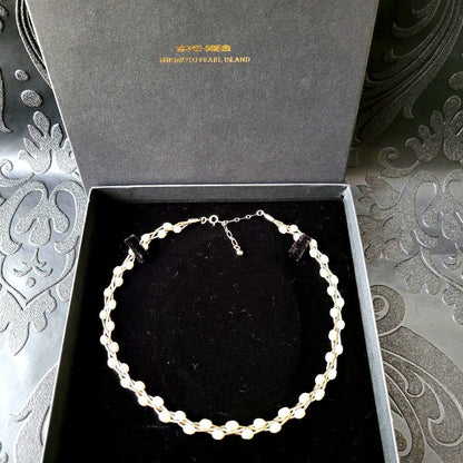 Elegant white Mikimoto Pearl Island pearl necklace with metal accents and adjustable clasp shown in dedicated box
