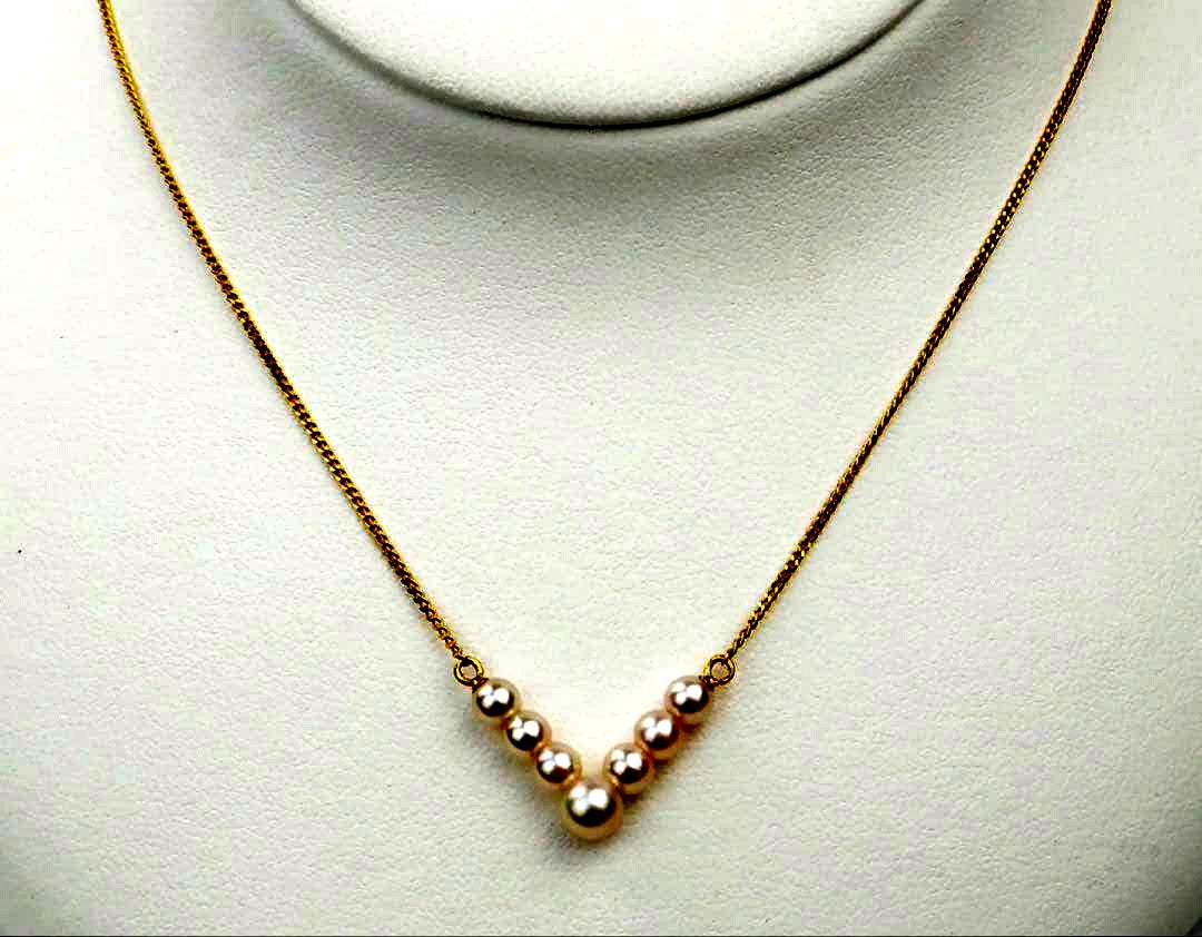 Akoya pearl necklace with V-shaped line and size-gradient pearls on a white background
