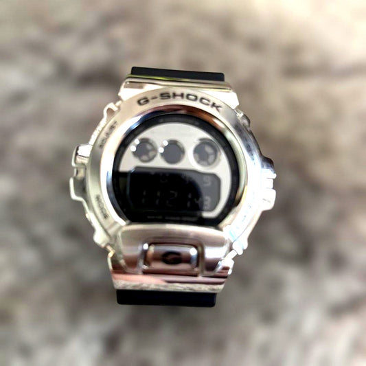 Casio G-Shock GM-6900U-1JF digital watch with black and silver metal bezel on white background