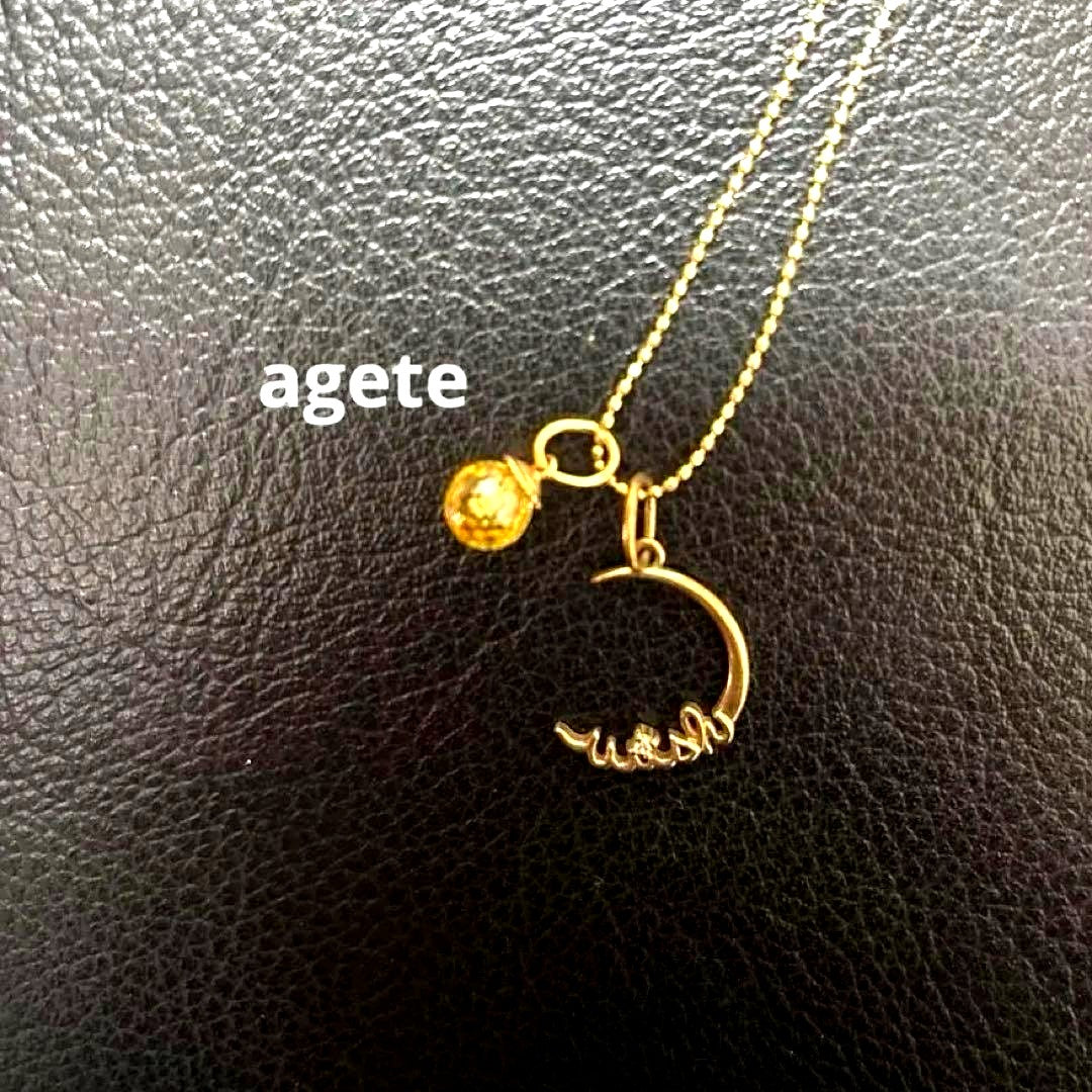 Agete gold pendant top with crescent moon and star motif on a white background