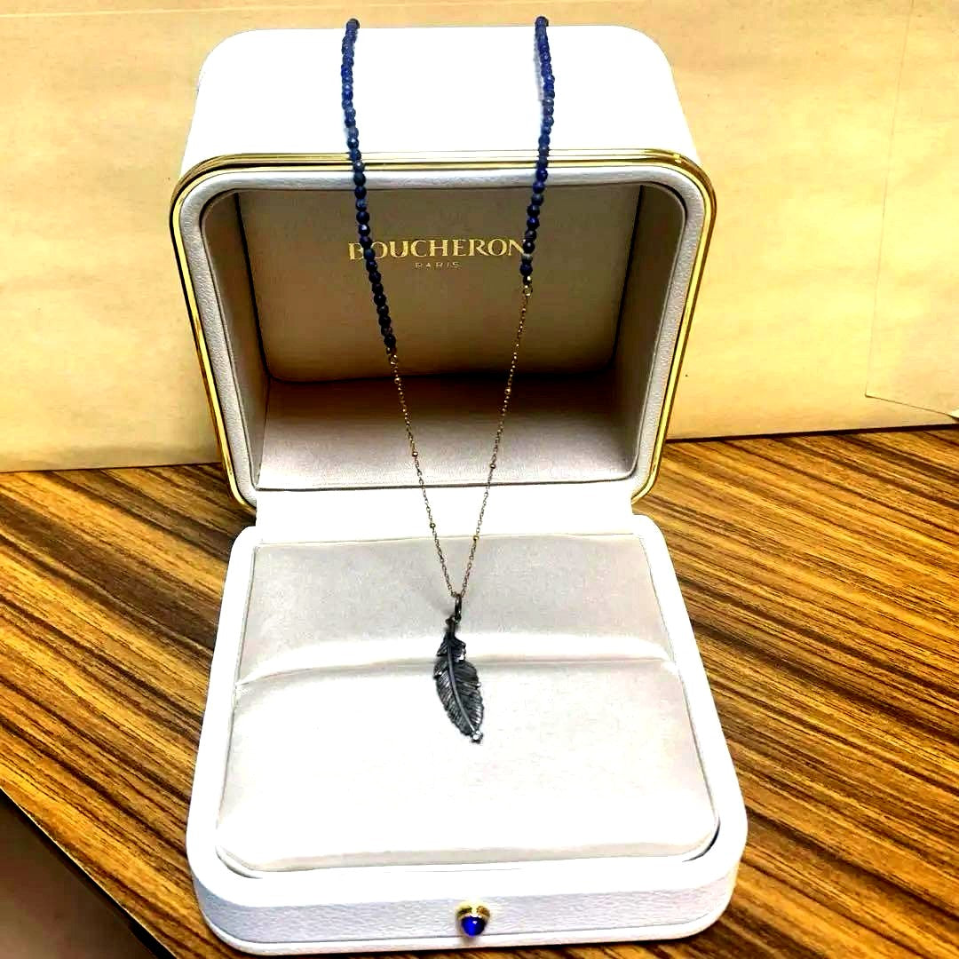 Agete necklace featuring navy lapis lazuli stone with 10 karat gold chain and silver feather charm set