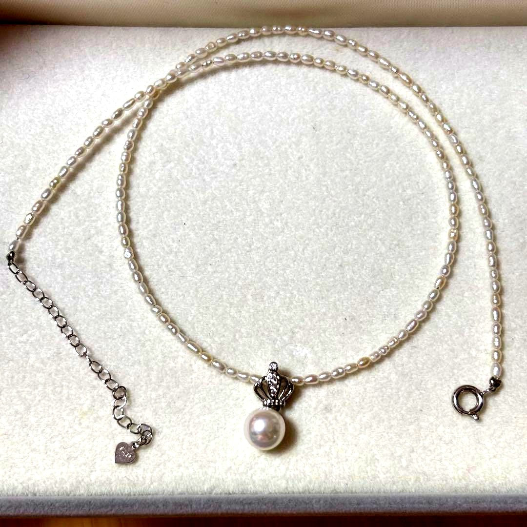Pearl and silver double necklace with crown motif pendant and lobster clasp on white background
