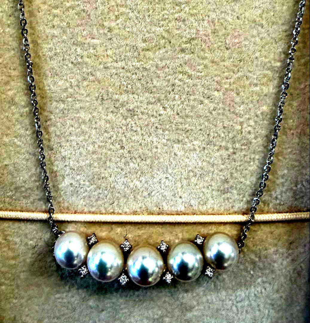 Pearl necklace adorned with sparkling diamonds displayed on a white background