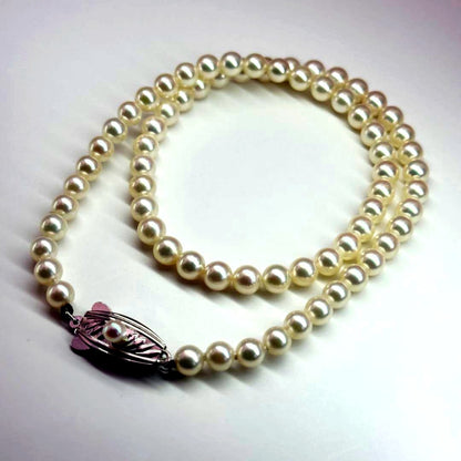 MIKIMOTO pearl necklace made of silver with round white pearls on a white background