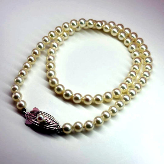 MIKIMOTO pearl necklace made of silver with round white pearls on a white background