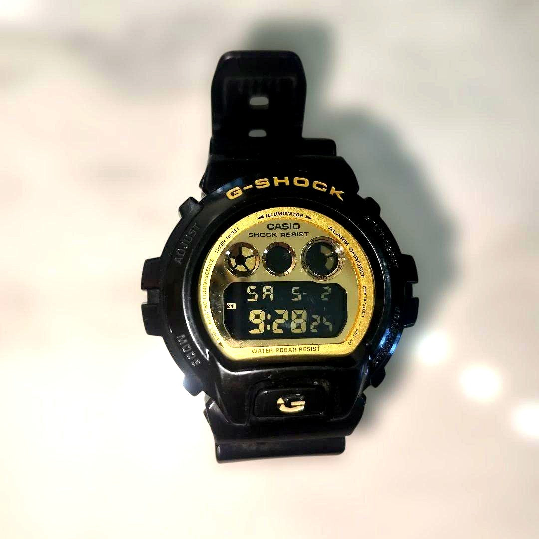 Casio G-Shock DW-6900CB black and gold watch with visible surface mark on G logo