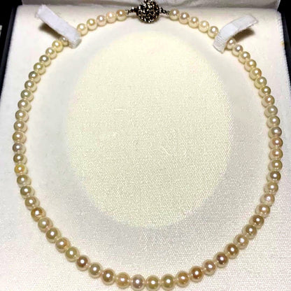 Akoya pearl necklace with 43 cm length and 6.1 to 5.5 mm round pearls on white background