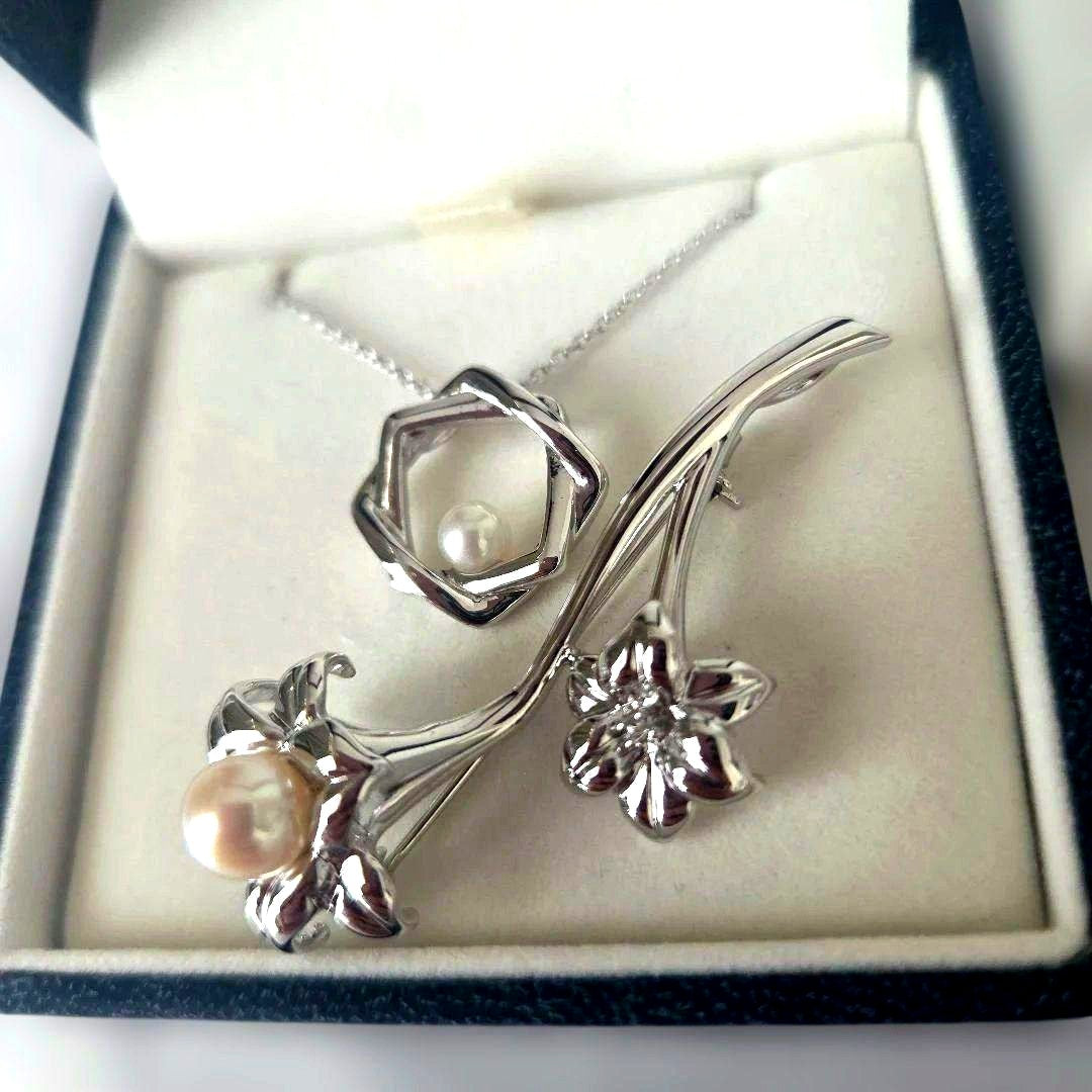 TASAKI pearl necklace with 6mm pearls and silver flower motif brooch set on white background
