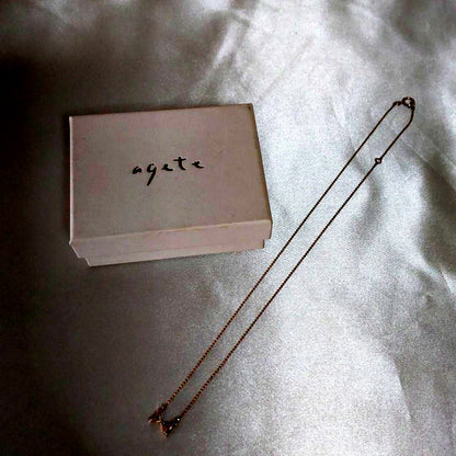 Beautiful agete ribbon-shaped necklace made of pink gold displayed on a white background