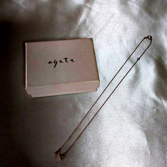 Beautiful agete ribbon-shaped necklace made of pink gold displayed on a white background