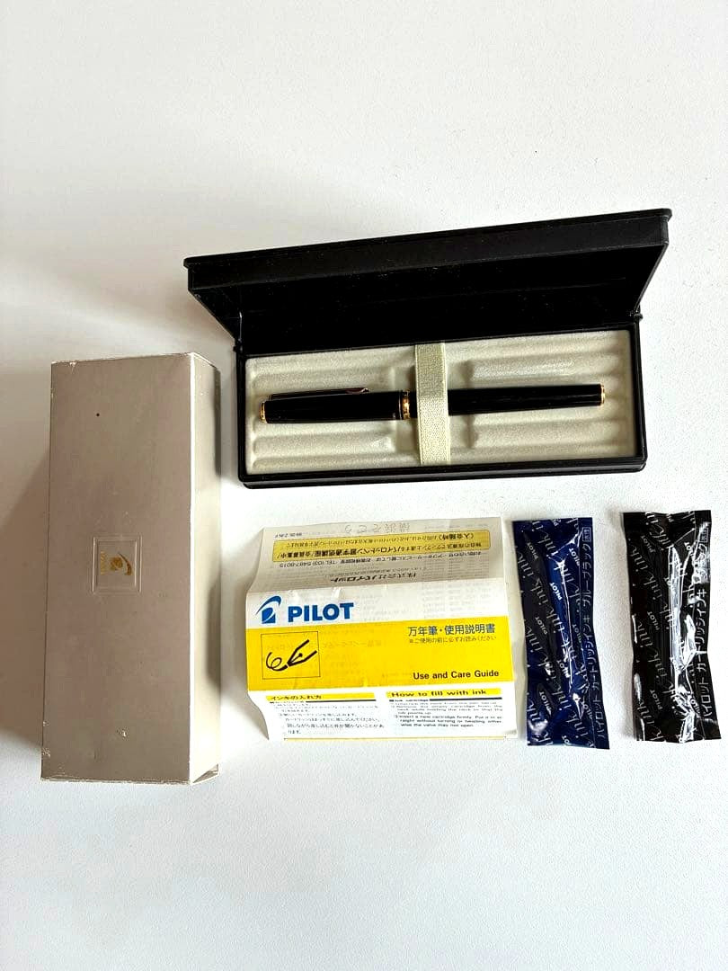 Pilot black fountain pen with medium gold-plated nib and included box, manual, and ink cartridges