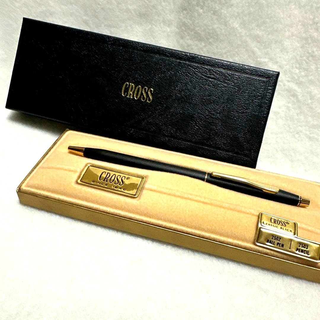 Cross USA black ballpoint pen with gold clip resting on white background with included case
