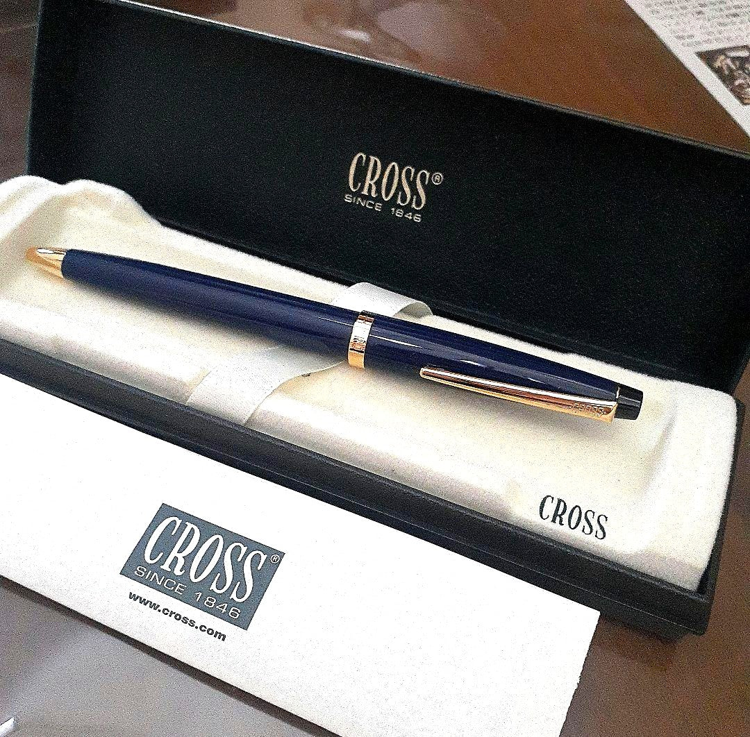 Cross ballpoint pen with navy metal body and gold finish beside its dedicated case