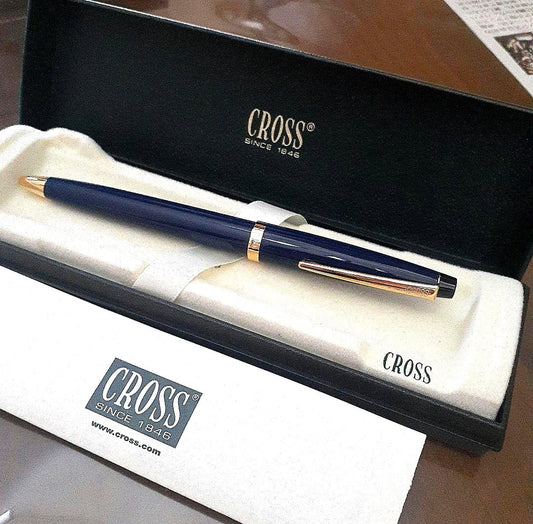 Cross ballpoint pen with navy metal body and gold finish beside its dedicated case