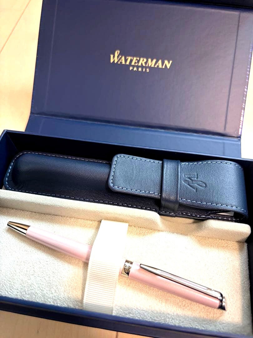 WATERMAN ballpoint pen with light pink body and twist mechanism next to its dedicated leather case