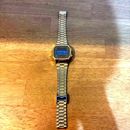 Gold Casio digital watch with alarm, chronograph, and EL backlight showing time on display