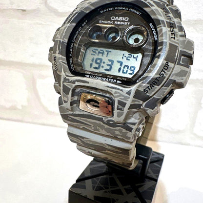 Used Casio G-Shock digital watch with camouflage design and waterproof feature, displayed with box and accessories