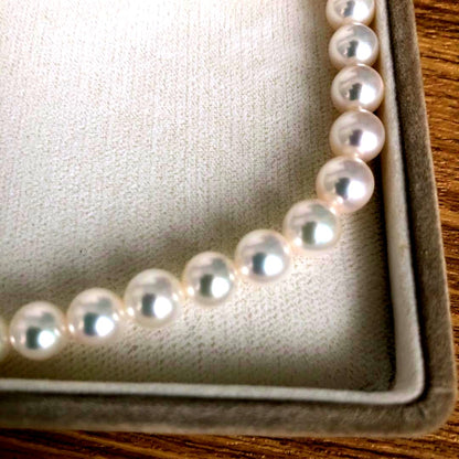 Elegant pearl necklace featuring 57 pearls and a silver clasp on a white background