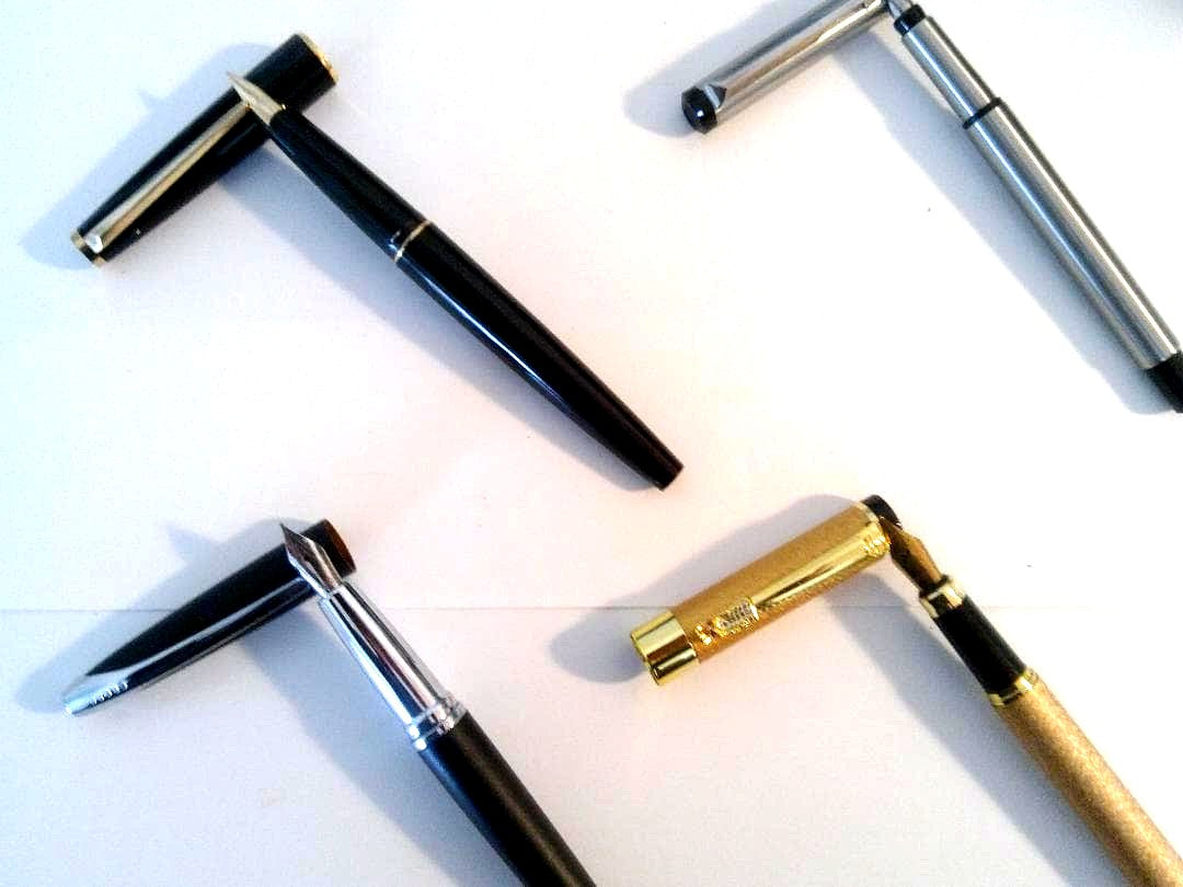 Montblanc Parker Cross Jinhao set of four pens including Montblanc model 310, displayed on white background
