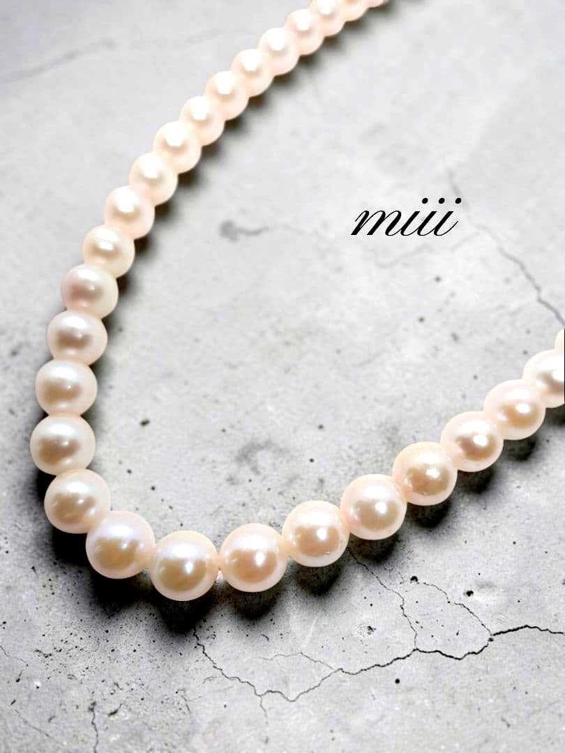 Close-up of an Akoya pearl necklace with 6.5-7mm pearls and a sterling silver clasp on a white background