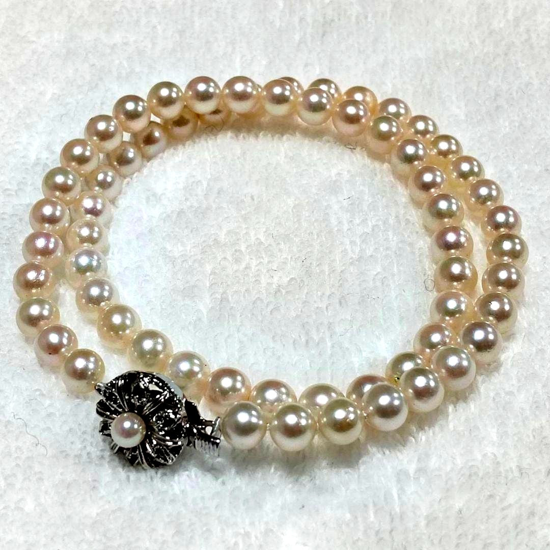 Akoya pearl necklace with 4-7mm white pearls and silver stamp clasp on a white background