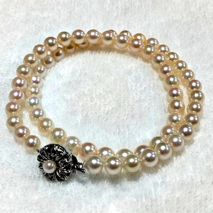 Akoya pearl necklace with 4-7mm white pearls and silver stamp clasp on a white background