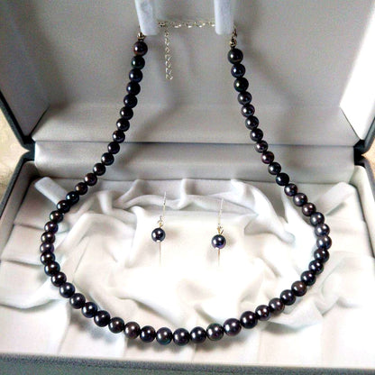 Akoya pearl necklace and matching earrings with silver clasp and findings on white background