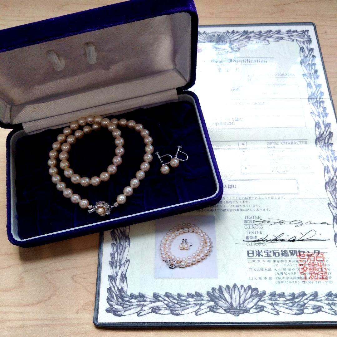 Akoya pearl necklace and matching earrings set with white pearls and silver clasp on a white background